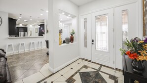 A modern interior with a kitchen area, white walls, and a tiled floor.