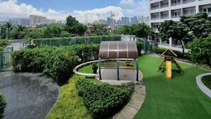 Un parque en la azotea con zona de juegos para niños, área de estar cubierta y vistas del horizonte urbano.
