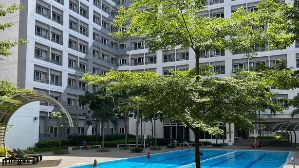 Un moderno edificio de apartamentos con piscina, mobiliario exterior y zonas verdes.