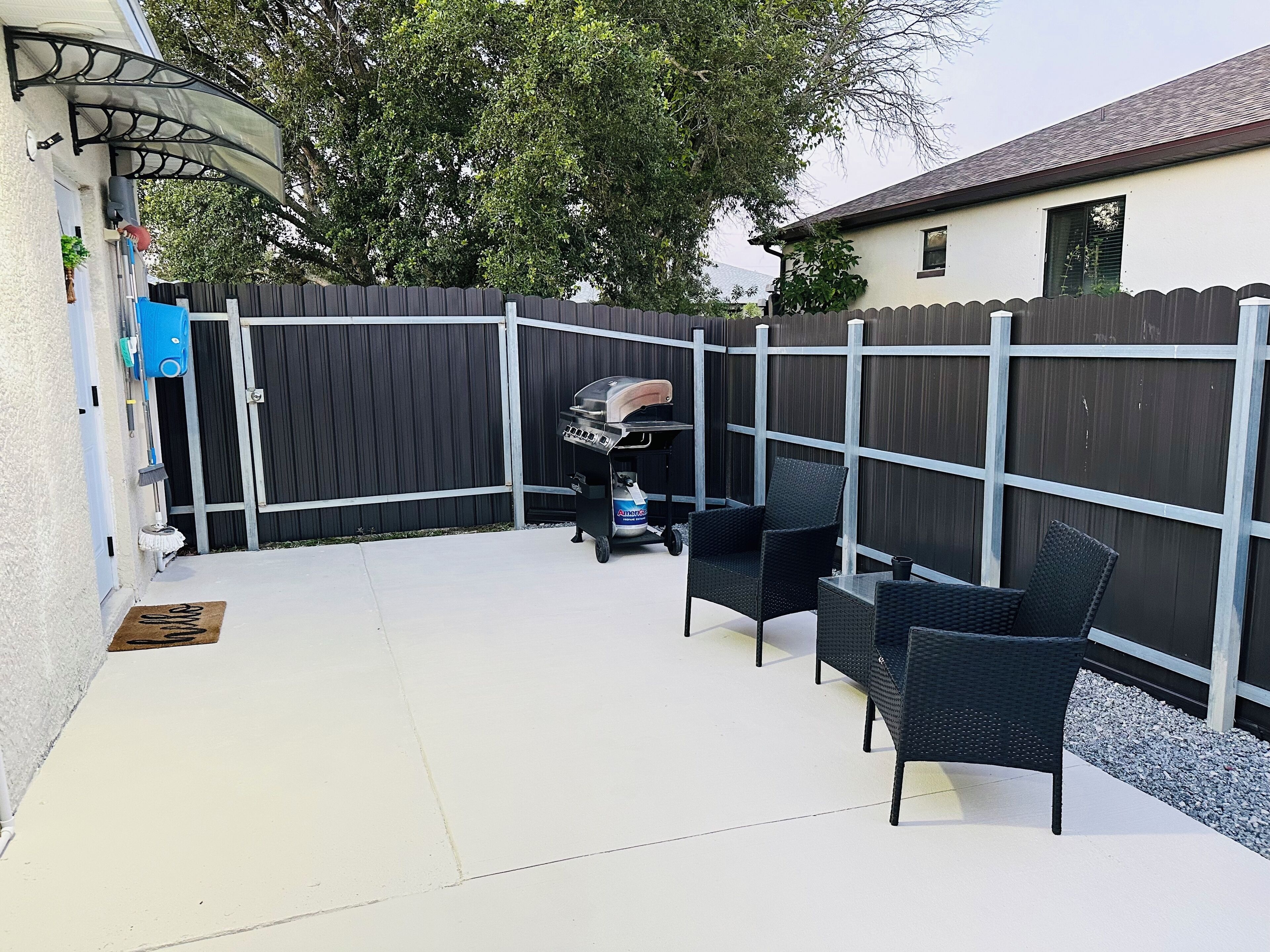 Eine Terrasse mit Grill, Stühlen und einem Zaun.