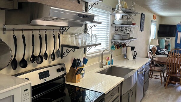 A modern kitchen with stainless steel appliances, wooden cabinets, and a dining area with a table and chairs. - Villa Cape San Blas - Gulf View Townhome, Steps from the Beach & Local Dining (cape san blaste)