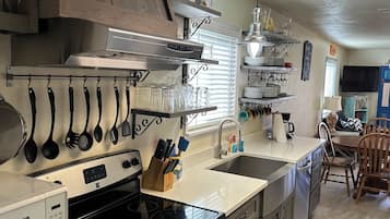 A modern kitchen with stainless steel appliances, wooden cabinets, and a dining area with a table and chairs.