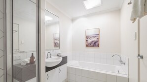 Un bagno moderno con uno specchio grande, un lavandino, una vasca e una doccia.