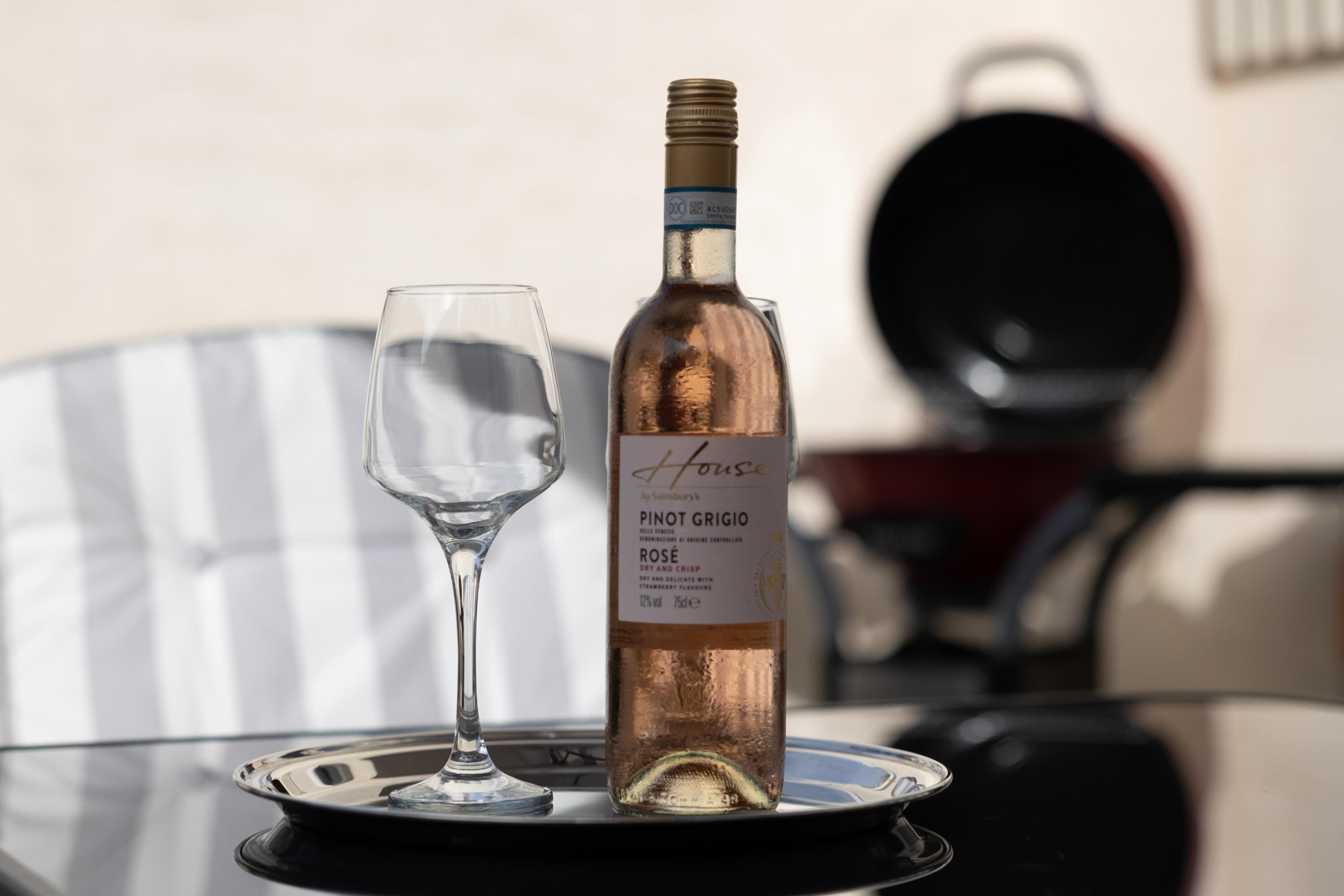 A bottle of Pinot Grigio Rose wine and a wine glass on a table.