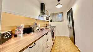 A narrow kitchen with a wooden countertop, a built-in oven, and a window with sheer curtains. - Casa Matilde 2 in Gerra Gambarogno, Gambarogno, Gerra, Switzerland (Gambarogno, Gerra)