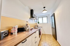 A modern kitchen with a wooden countertop, a range hood, a built-in oven, and a window with curtains. - Casa Matilde 1 in Gerra Gambarogno, Gambarogno, Gerra, Switzerland (Gambarogno, Gerra)