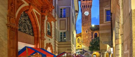 Une rue historique, bordée d’édifices à l’architecture remarquable, avec un beffroi et des terrasses extérieures.