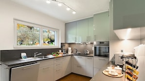 A modern kitchen with a dishwasher, sink, and coffee maker, with a view of trees outside. - Casa Mima 1 Gerra Verzasca for 4, Gerra Verzasca, Switzerland (Gerra Verzasca)