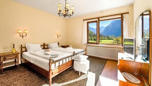 A bedroom with a wooden bed, bedside lamps, a view of mountains, a radiator, and a television. - Casa Mima 1 Gerra Verzasca for 4, Gerra Verzasca, Switzerland (Gerra Verzasca)