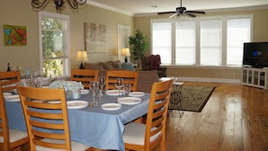 A dining area with a table set for six, wooden chairs, a chandelier, and a ceiling fan.