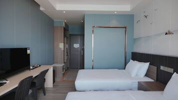 A hotel room with two beds, a desk with a chair, a television, and a wardrobe.