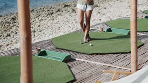 Una persona juega al golf en una playa con una estructura de madera sobre ella.
