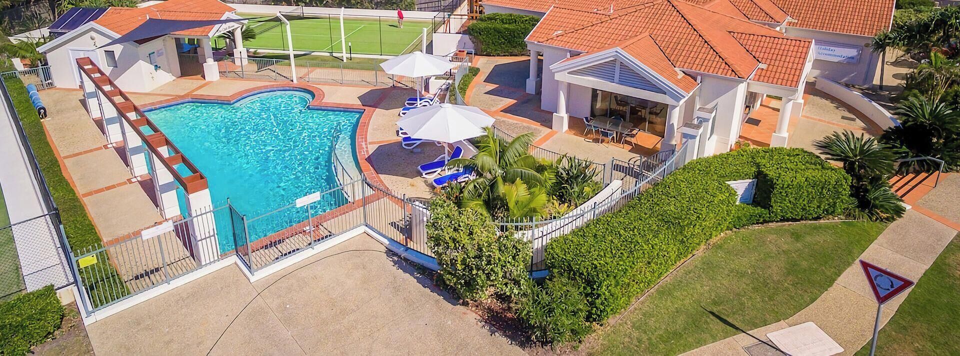 Um imóvel residencial com piscina, área de estar externa e quadra de tênis.