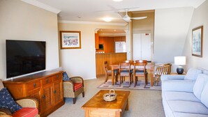 A living room with a television, sofa, dining table, and chairs. - Breakers 1/10- Stone Real Estate Yamba (Yamba)