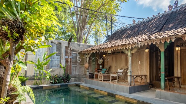 Una casa tradicional de madera con techo de tejas, piscina y mobiliario exterior.