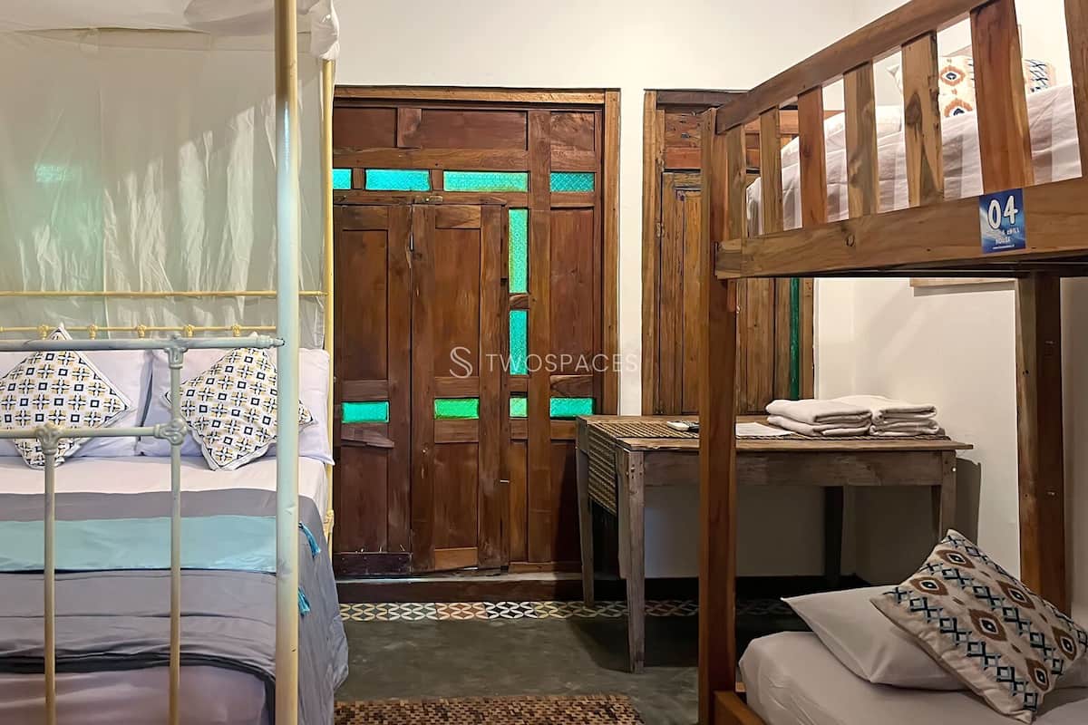 A room with a bunk bed, a small table with towels, and a wooden door with green glass panels.