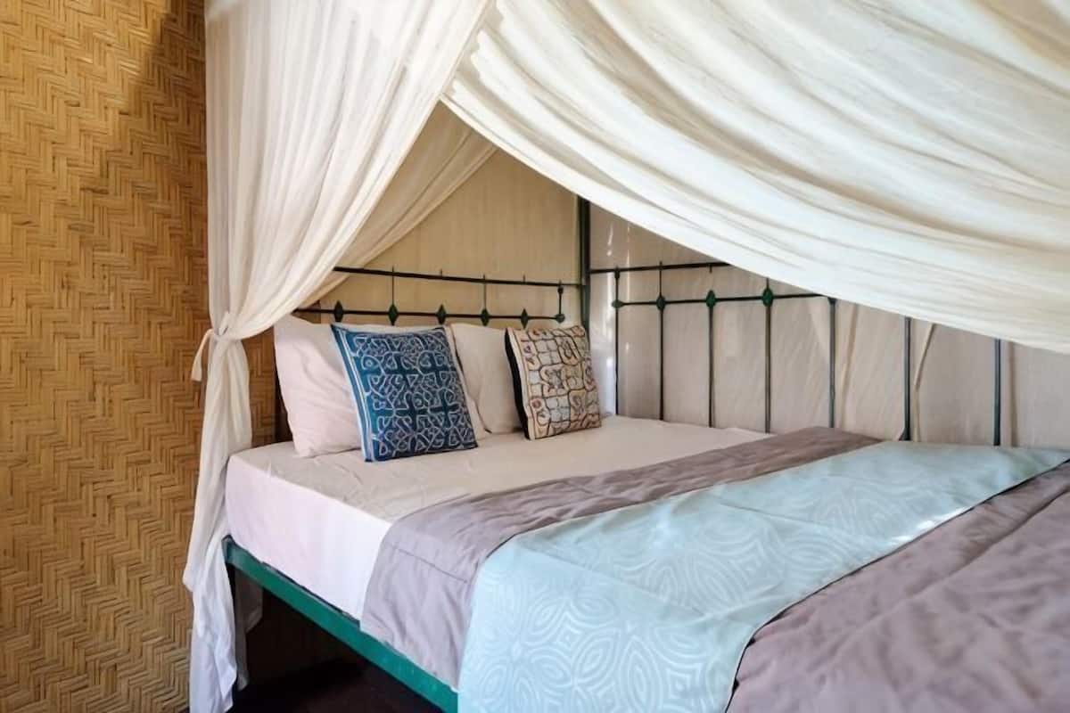 A bed with a canopy, a patterned wall, and a green bed frame.