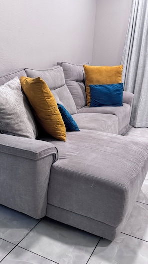 Ein graues Sofa mit vielen Kissen in einem Wohnzimmer.