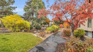 A residential area with a paved walkway, benches, and various trees in autumn colors. - Stylish 2BR Walk to Ski Slopes (Park City)