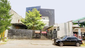 A modern building with a sign 'de leota kost' and a gated entrance with a car parked in front. - OYO Life 90388 De'leota (Semarang)