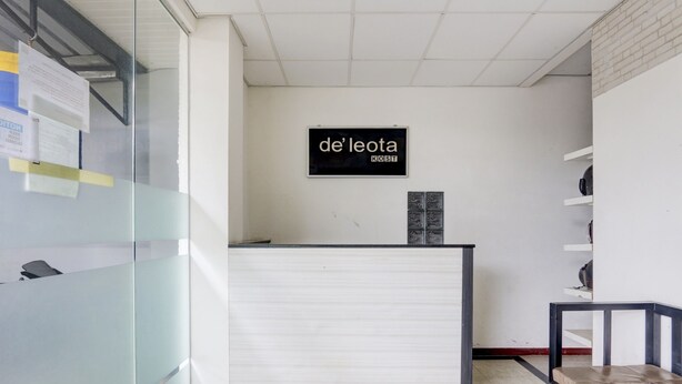 A reception desk with a sign reading "de leota KOSTT" in a modern office setting. - OYO Life 90388 De'leota (Semarang)