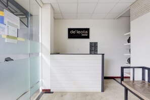 A reception desk with a sign reading "de leota KOSTT" in a modern office setting.