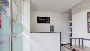 A reception area with a closed shutter, a sign reading "de leota", and a bench. - OYO Life 90388 De'leota (Semarang)