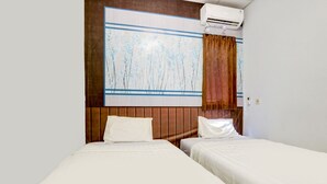 A hotel room with two beds, a large abstract painting on the wall, wooden paneling, and an air conditioning unit. - OYO Life 90388 De'leota (Semarang)