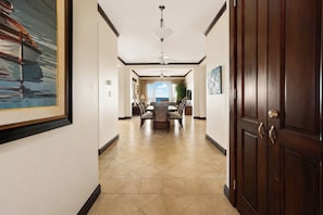 A hotel hallway with a dining area, a ceiling fan, and a large wooden door.