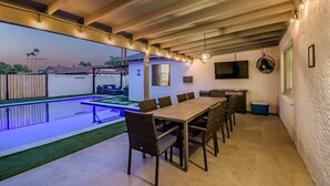 Eine überdachte Terrasse im Freien mit Pool, Essbereich und Sitzgelegenheiten.