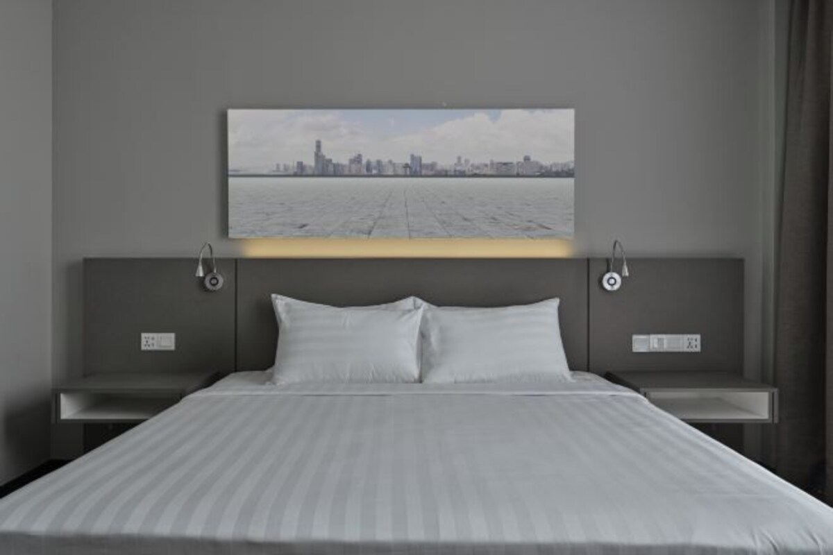 Une chambre d’hôtel moderne dotée d’un grand lit, offrant une vue sur la ville et présentant un design minimaliste.
