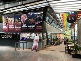 Restaurante com interior moderno, apresentando piso de tijolos e diversas opções de assentos, incluindo mesas e cadeiras.