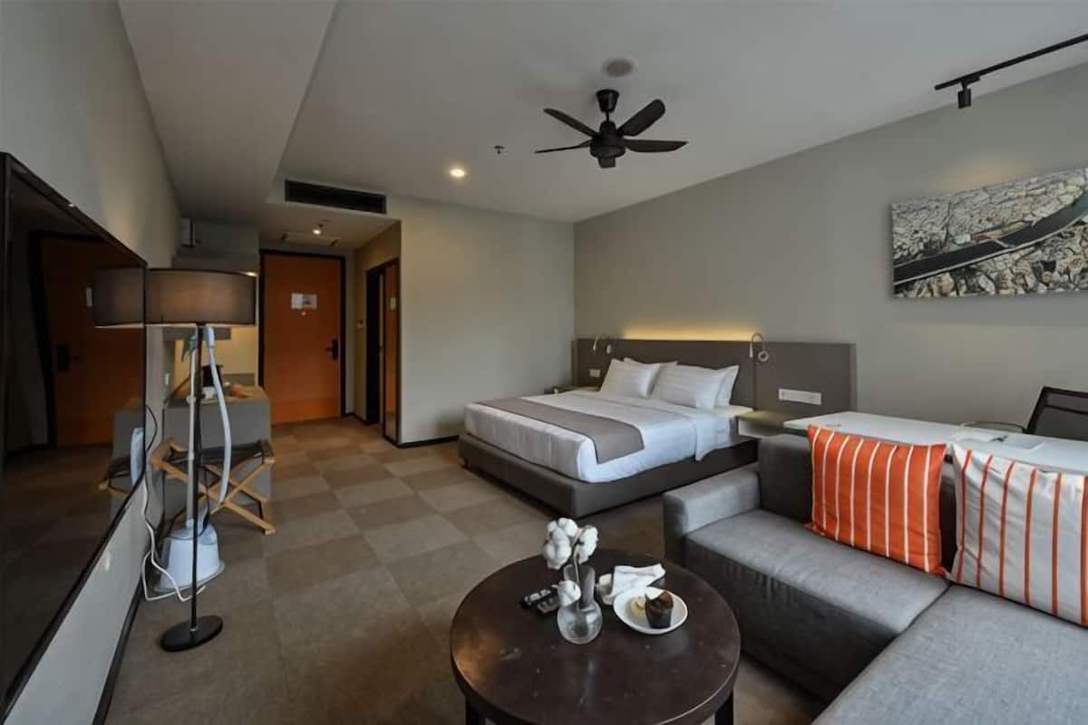 Ein Hotelzimmer mit Bett, einer Couch, einem Couchtisch, einem Schreibtisch und einem Deckenventilator.