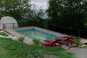 A rectangular swimming pool with a wooden deck and lounge chairs. - Glamping Dream Domes Ismayilli (Ismailli)