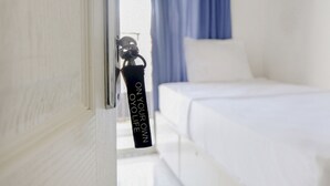 A hotel room with a bed, a window with curtains, and a keychain hanging on the door. - OYO Life 2760 Kost Simpang Borobudur 47 (Malang)