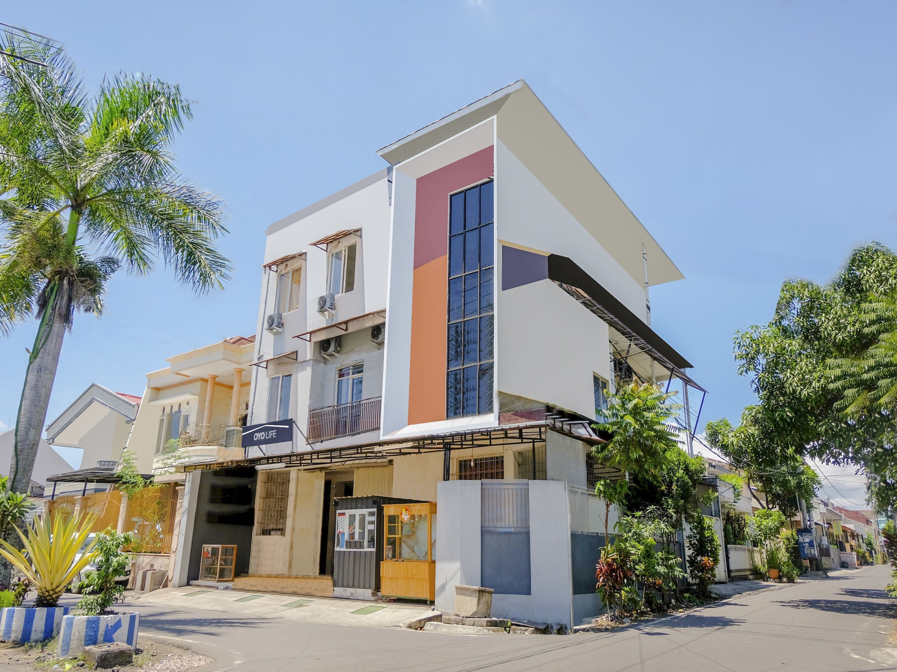A modern two-story building with a flat roof, large windows, and a visible sign for 'OYO LIFE'.