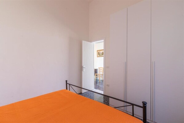 Une chambre à coucher avec un lit, une porte donnant sur une autre pièce et un escalier.