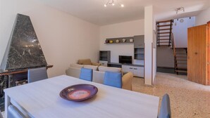 A modern living room with a dining table, sofa set, and a kitchen area with a TV and shelves. - Villa 400 meters from the beach with equipped garden, internal parking and three bedrooms in Torre S (Melendugno)