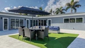 A modern outdoor patio with a dining table, chairs, and a sofa. - 2009 B Sunshine Manors (Wilton Manors)