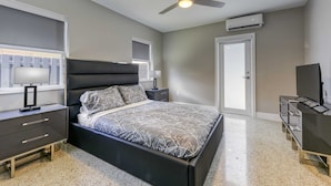 A bedroom with a bed, a nightstand, a dresser, a ceiling fan, and an air conditioning unit. - 2009 B Sunshine Manors (Wilton Manors)
