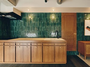 A kitchen with a wooden cabinet layout, a black faucet, and green tiled backsplash. - illi Com Shimokitazawa (Tokyo)