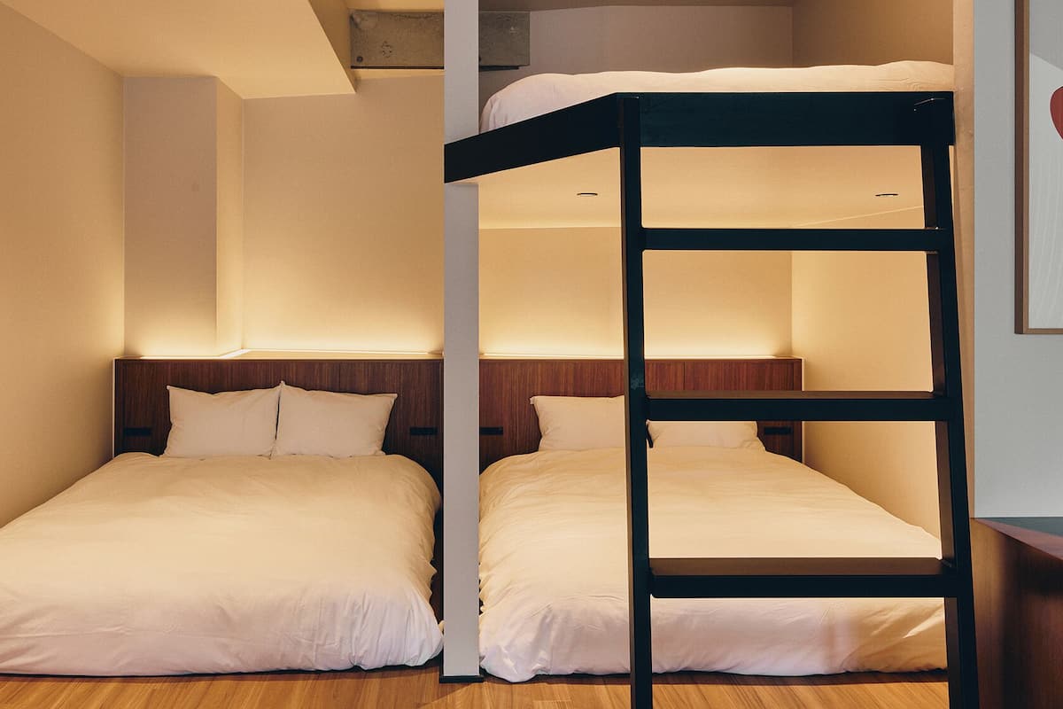Una habitación con dos literas, suelo de madera y cabecera con iluminación integrada.