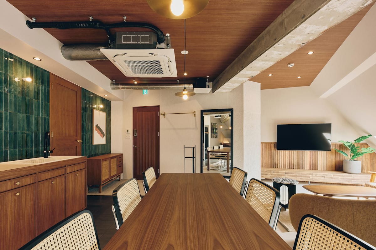 Un salón de conferencias con una larga mesa de madera, sillas y un televisor en la pared.