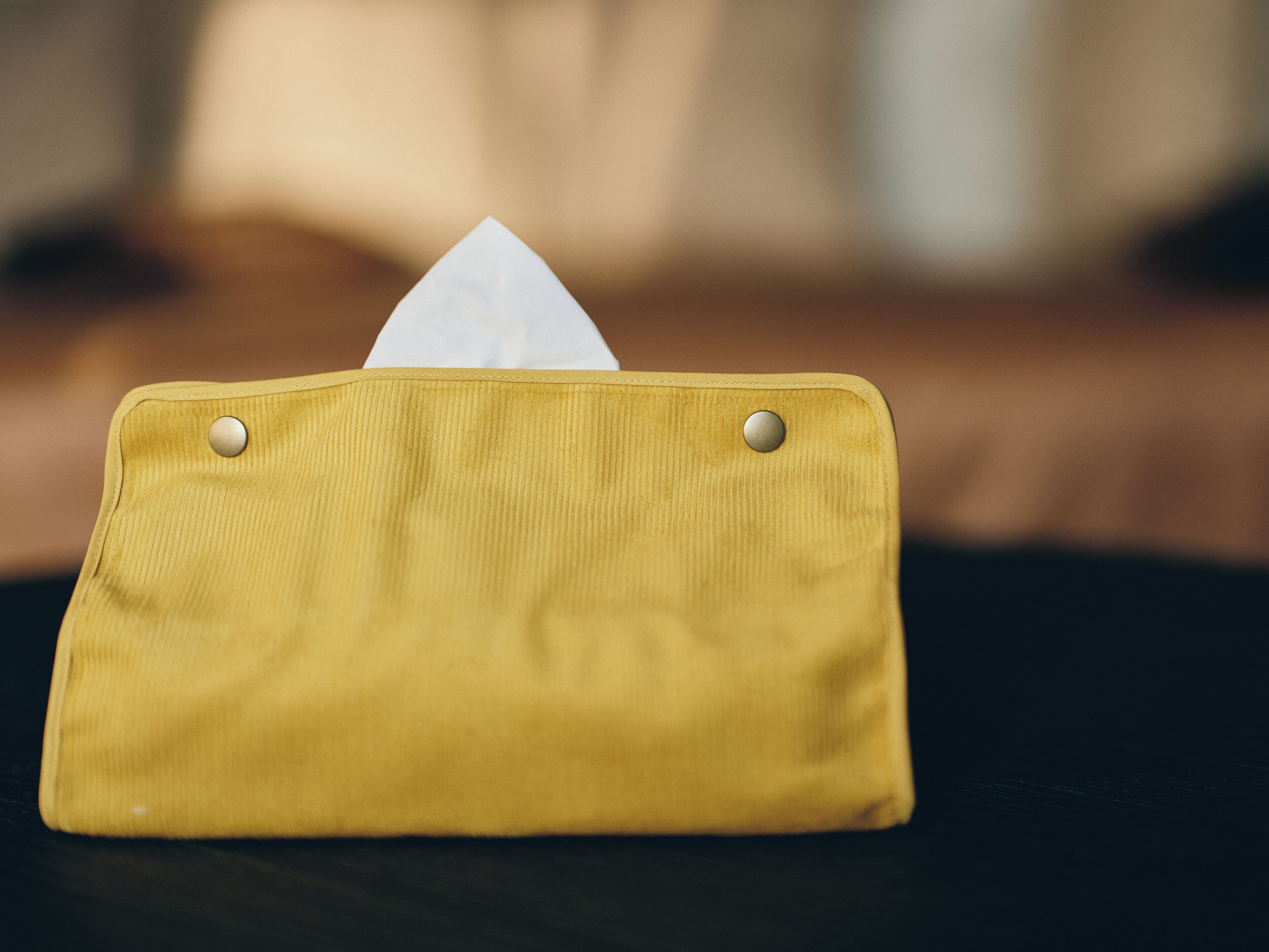 A yellow fabric pouch with a white tissue inside, placed on a dark surface.