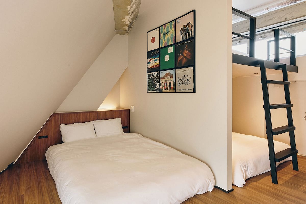 Un dormitorio con cabecera de madera, una litera y una escalera.
