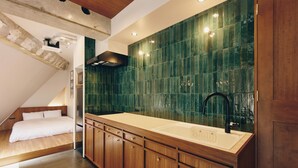 Een moderne keuken met houten kastjes, een grote gootsteen en een groene tegeltjeswand.