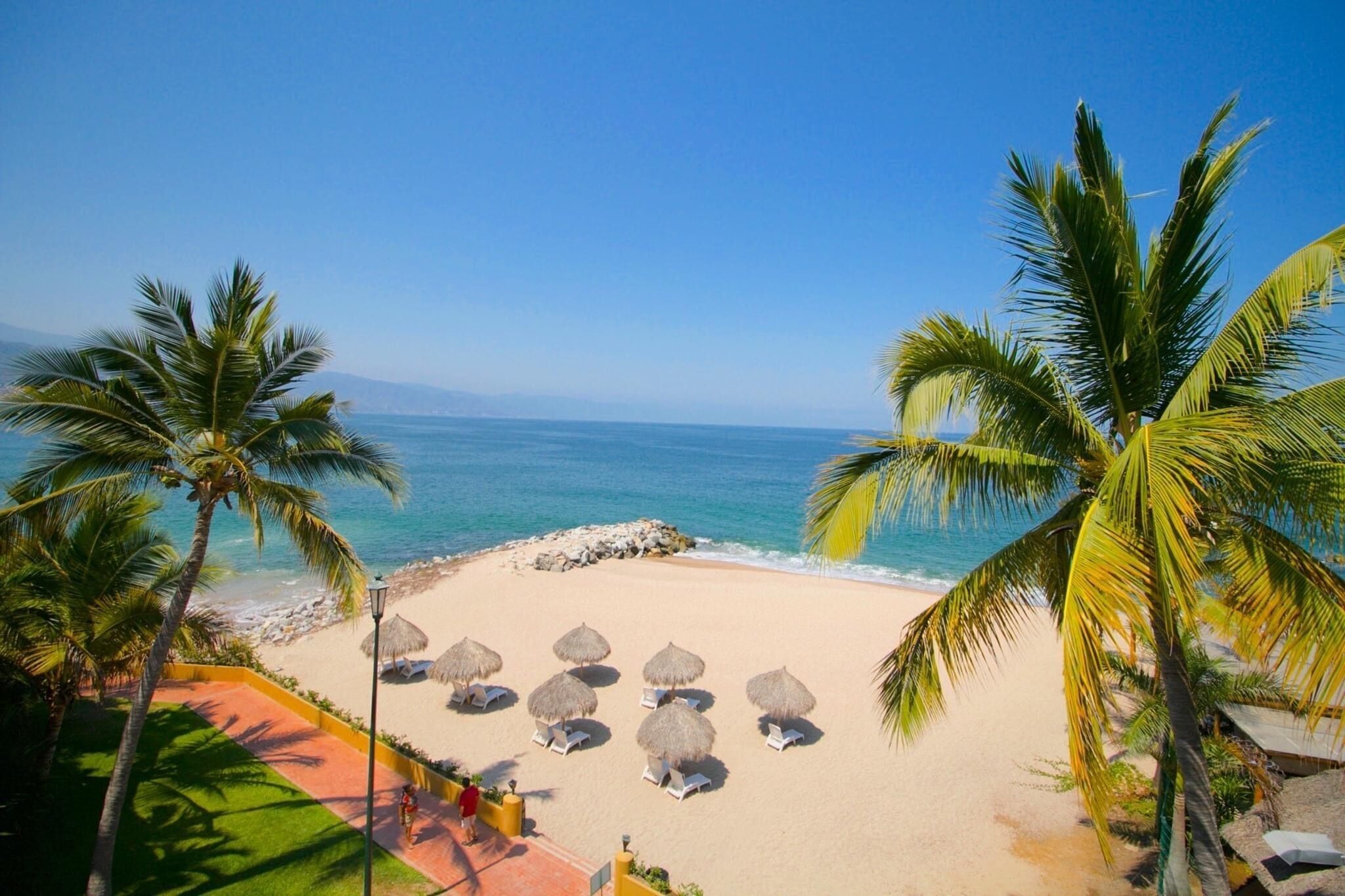På stranden, hvidt sand, liggestole, parasoller