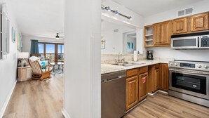 A modern kitchen with wooden cabinets, stainless steel appliances, and a large window. - BEACHFRONT Views at La Mirage Condo 335  |  Beachfront Resort Condominiums with Private Boardwalk (Port Aransas)