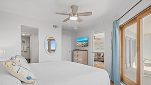 A bedroom with a bed, a ceiling fan, a television, and a view of the outdoors through a sliding door. - BEACHFRONT Views at La Mirage Condo 335  |  Beachfront Resort Condominiums with Private Boardwalk (Port Aransas)