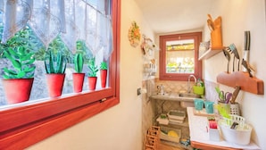A kitchen with potted plants on the window sill, a sink, and various kitchen utensils on the wall. - La Piccola Casa Dell'uva Fragola Next to the Lake (Meina)